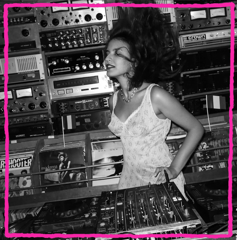 Jeune femme brune en robe devant des platines de DJ