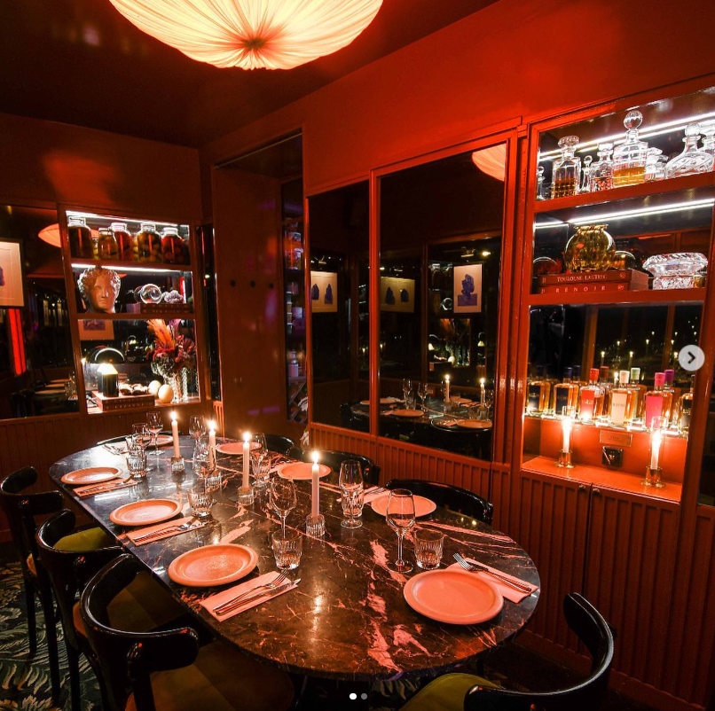 Table élégante dressée pour un dîner intime à Maison Lautrec à Paris, avec bougies allumées, vaisselle raffinée, et vitrines de spiritueux. Ambiance chaleureuse et feutrée idéale pour les événements CrushParty.