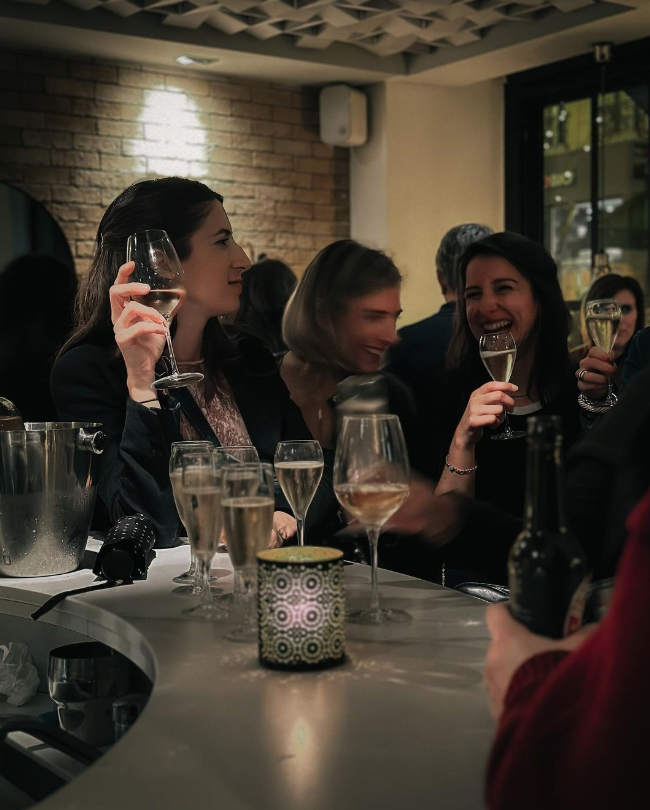 femmes qui rient dans un bar, un verre de vin à la main