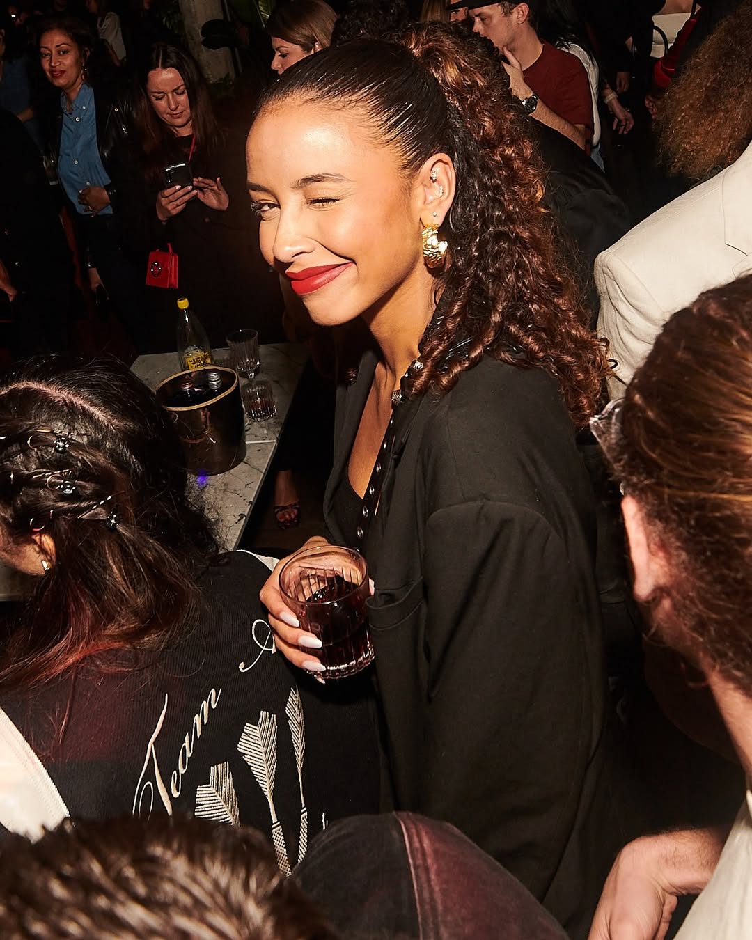 Femme souriante et clin d’œil à la caméra lors d'une soirée célibataires au Kube Hotel, ambiance chaleureuse et joyeuse.